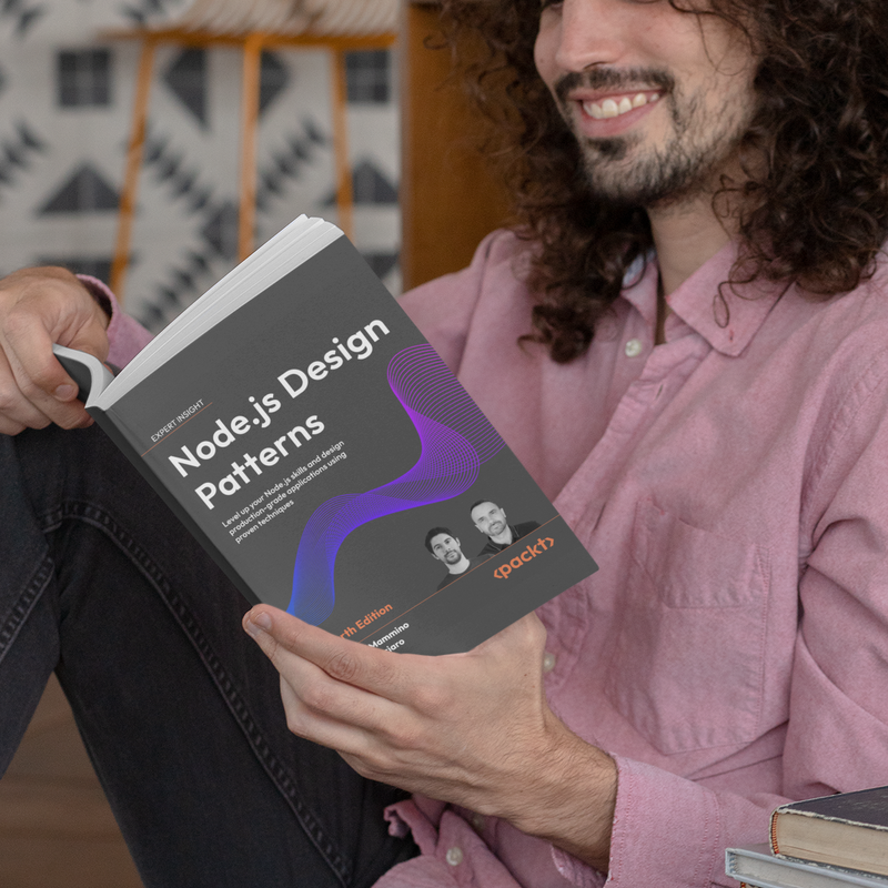 Man with long curly hair and a pink shirt sitting on outdoor steps, reading the book "Node.js Design Patterns, Fourth Edition" by Luciano Mammino and Mario Casciaro.