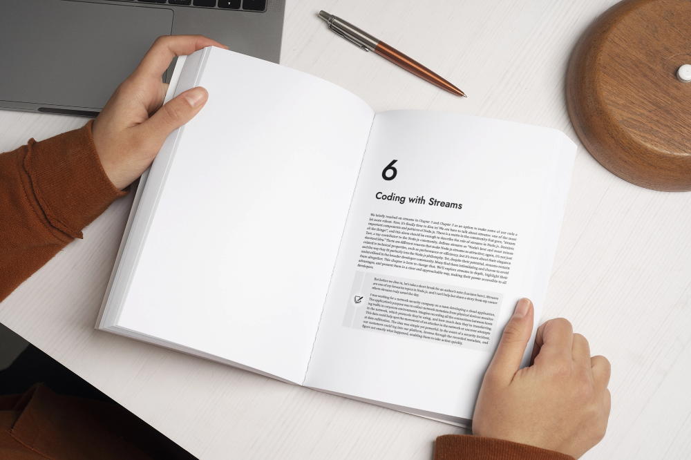A person holding a copy of Node.js Design Patterns open on Chapter 6: Coding with Streams